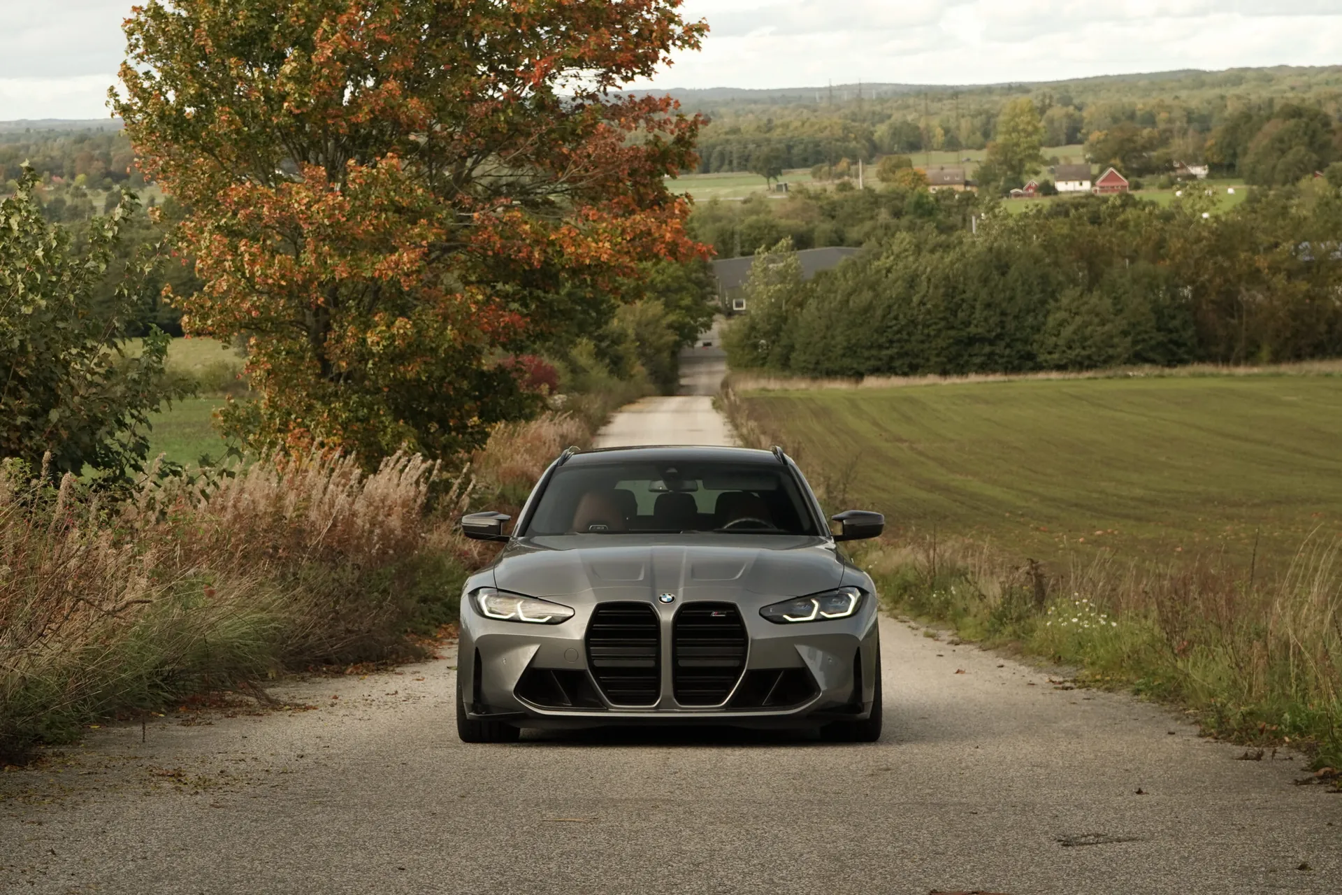 Grå BMW M3 på en skånsk landsväg omgiven av höstfärgade träd